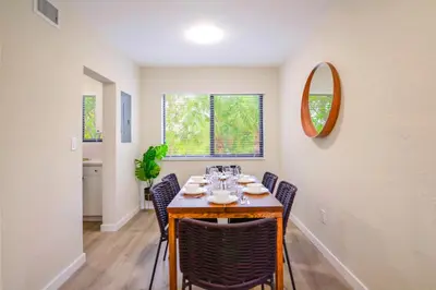 a dining room with a table with chairs and a mirror at Modern Apartment in Prime Miami Location in Miami