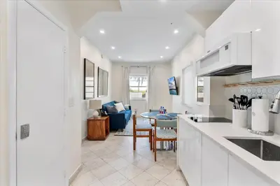 a kitchen and living room with white cabinets and a table at Cozy Miami Beach Apartment walking distance to Beach and Ocean in Miami Beach