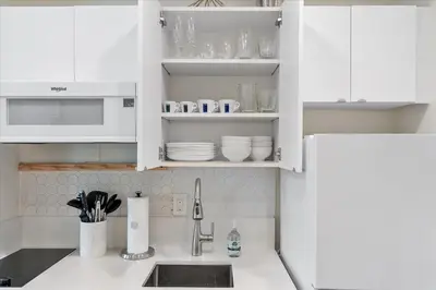 a white kitchen with a sink and white cabinets at Cozy Miami Beach Apartment walking distance to Beach and Ocean in Miami Beach