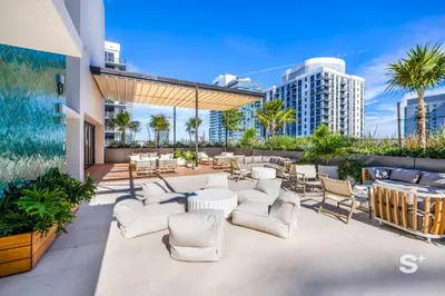 a patio with white chairs and tables and a building at Modern and Cozy 1BD Apt with Gym & Pool in Miami