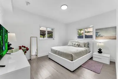 a white bedroom with a bed and a tv at Cozy house with a pool in Miami in Miami