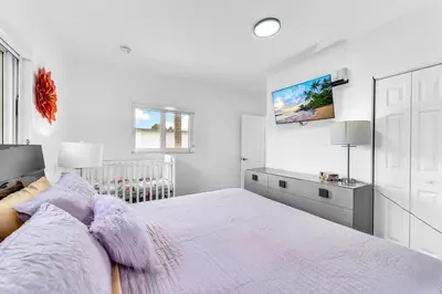 a white bedroom with a large bed with purple blankets at Cozy house with a pool in Miami in Miami