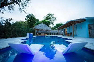 a swimming pool with white chairs and a house at Las Tortugas Modern Oasis Getaway Many Amenities in Fort Lauderdale