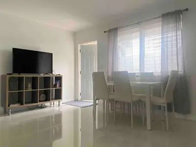 a dining room with a table and chairs and a television at Florida Cozy Home!!! in Hallandale Beach