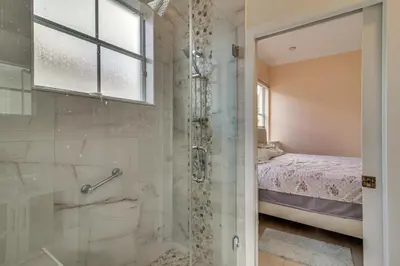 a bathroom with a walk in shower next to a bed at Great for Gatherings! Sleek and Relaxing Hialeah Gem in Hialeah