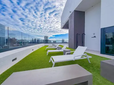 a row of white lounge chairs on the roof of a building at City Skyline Views & Rooftop Pool at District 225 in Miami