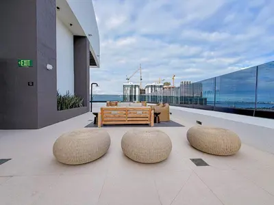 a balcony with two stools and a couch on a building at City Skyline Views & Rooftop Pool at District 225 in Miami