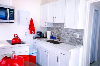 a white kitchen with a sink and a microwave at Villa Clara EPIC-Little Havana in Miami
