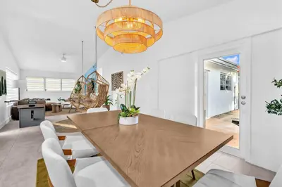 a dining room with a wooden table and white chairs at Palm Fiction - Pool and Hard Rock Casino in Hollywood