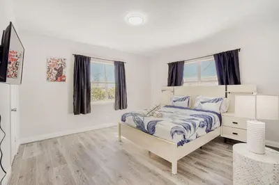 a white bedroom with a bed and two windows at Lauderdale Breeze Villas - Luxury 3 BR Coastal Retreat in Fort Lauderdale