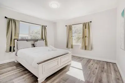 a white bedroom with a bed and two windows at Lauderdale Breeze Villas - Luxury 3 BR Coastal Retreat in Fort Lauderdale