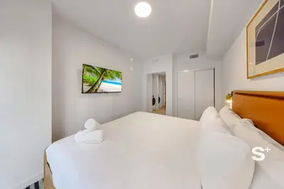 a white bedroom with a large bed and a tv at Luxurious & Stylish 2BD Apt in Miami Gym & Pool in Miami