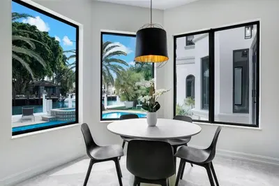 a dining room with a table and chairs and windows at WATERFRONT MANSION Las Olas in Fort Lauderdale