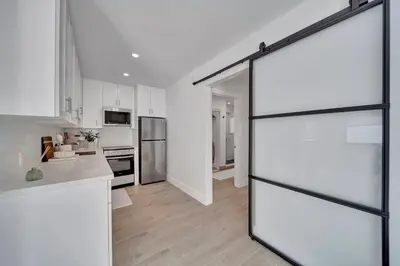 a kitchen with white cabinets and a sliding glass door at Waterfront Unit #2 20 Min Walk to Beach and Shops in Fort Lauderdale