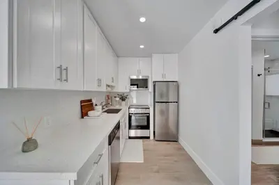 a kitchen with white cabinets and a stainless steel refrigerator at Waterfront Unit #2 20 Min Walk to Beach and Shops in Fort Lauderdale