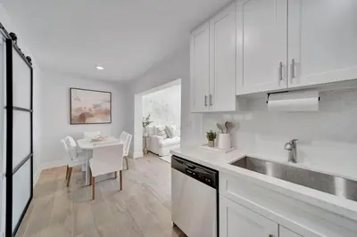 a kitchen with white cabinets and a table with chairs at Waterfront Unit #3 20 Min Walk to Beach and Shops in Fort Lauderdale