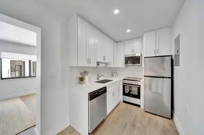 a kitchen with white cabinets and a stainless steel refrigerator at Waterfront Unit #3 20 Min Walk to Beach and Shops in Fort Lauderdale