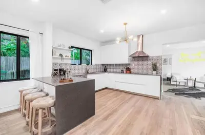 a kitchen with white cabinets and a island with bar stools at Sunny Miami Escape in Prime Location