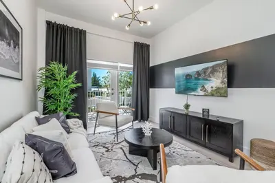 a living room with a white couch and a table at Classy 2BR-2BA Oasis Beach Pool Parking EV Station in Hallandale Beach