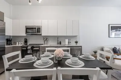 a kitchen with a dining room table with white cabinets at Classy 2BR-2BA Oasis Beach Pool Parking EV Station in Hallandale Beach