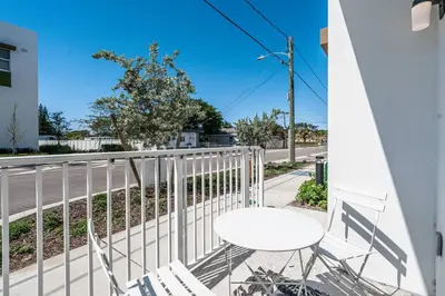 a white table and chairs on a balcony with a street at Classy 2BR-2BA Oasis Beach Pool Parking EV Station in Hallandale Beach