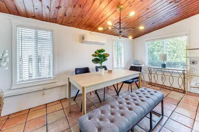 a dining room with a table and chairs and windows at 5 Mi to Las Olas Beach! Bright Home with Fenced Yard in Fort Lauderdale