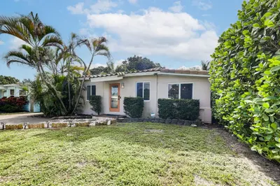 a house with a large hedge in front of it at 5 Mi to Las Olas Beach! Bright Home with Fenced Yard in Fort Lauderdale