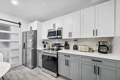 a kitchen with white cabinets and stainless steel appliances at Miami Hotel Home in North Miami