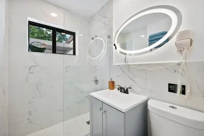 a white bathroom with a sink and a mirror at Miami Hotel Home in North Miami