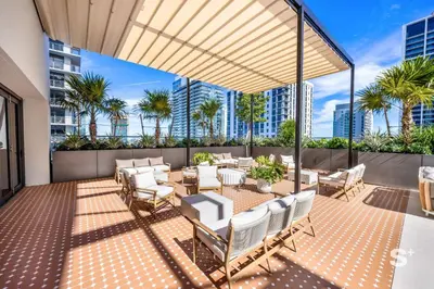 a patio with tables and chairs and palm trees at Cozy Ensuite 1BR Apartment in DTW Miami in Miami