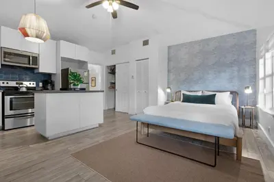a bedroom with a white bed and a kitchen at 7BD Downtown Oasis - Pool - 10 Mins to South Beach in Miami