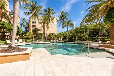 a swimming pool with palm trees and a building at Resort Condo By Aventura Mall! Gated Community in Aventura