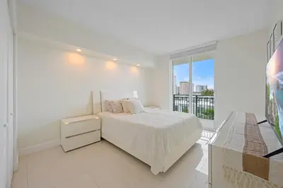 a white bedroom with a bed and a large window at Spacious 3BR Condo Across from Beach with Ocean & City Views in Sunny Isles Beach