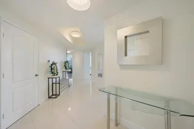 a white hallway with a glass table and a white door at Spacious 3BR Condo Across from Beach with Ocean & City Views in Sunny Isles Beach
