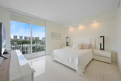 a white bedroom with a bed and a large window at Spacious 3BR Condo Across from Beach with Ocean & City Views in Sunny Isles Beach