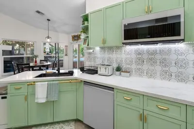 a kitchen with green cabinets and white counter tops at Plantation Pool Home with Hot Tub Sleeps 10 in Plantation