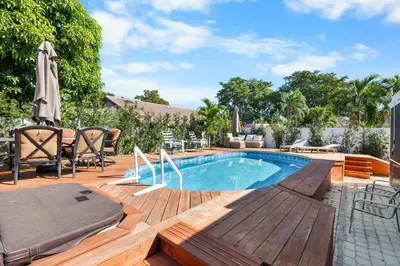 a swimming pool with a wooden deck and a wooden deck at Plantation Pool Home with Hot Tub Sleeps 10 in Plantation