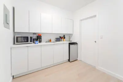 a white kitchen with white cabinets and a refrigerator at Miami Studio a Few Steps to the Beach in Miami