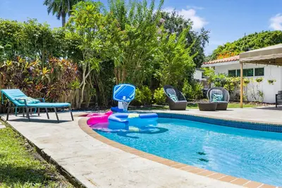 a swimming pool with chairs and a blue and pink pool toy at Spacious Miami Home with Private Pool & Parking in Biscayne Park