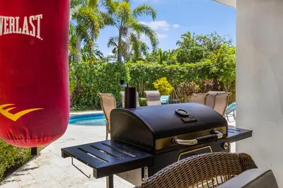 a grill with a table and chairs next to a pool at Spacious Miami Home with Private Pool & Parking in Biscayne Park