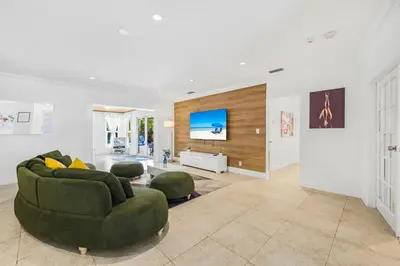 a living room with a green couch and a tv at Spacious Miami Home with Private Pool & Parking in Biscayne Park
