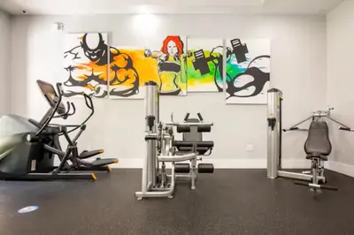 a gym with cardio equipment and paintings on the wall at The Yacht Club at Aventura Miami 4405 in Aventura