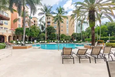 a pool at a resort with chairs and palm trees at The Yacht Club at Aventura Miami 4405 in Aventura