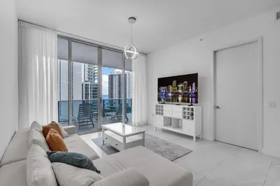 a white living room with a couch and a tv at Chic OceanView 2 Bedroom with Free Parking Pool Jacuzzi in Sunny Isles Beach