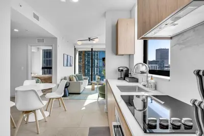 a kitchen with white countertops and a living room at Corner Chic 2 Bedroom Downtown with Rooftop Pool & Views in Miami