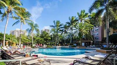 a swimming pool with chaise lounge chairs and palm trees at The Yacht Club at Aventura Miami 3405 in South Island