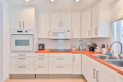 a white kitchen with white cabinets and a sink at Family Grand Advantage in Hollywood