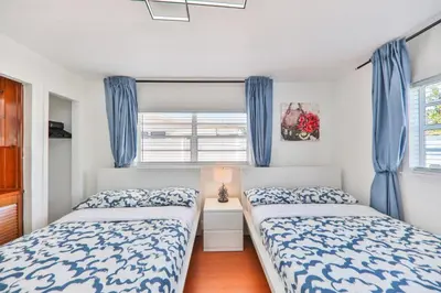 two beds in a bedroom with blue curtains at Oasis of Love and Joy Family in Miami