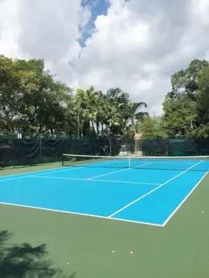 a blue tennis court with trees in the background at The Yacht Club at Aventura Miami 9505 in South Island