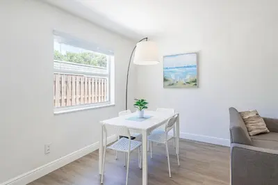 a white dining room with a white table and chairs at Modern 2BR Stay with Desk, Patio, BBQ, Free Parking in Fort Lauderdale